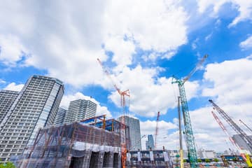 An unfinished high-rise apartment complex with idle cranes under an overcast sky.