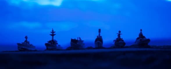 Military aircraft silhouetted against a smoky orange sky at dusk