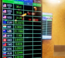 A currency exchange board showing multiple currency symbols on a modern trading floor.