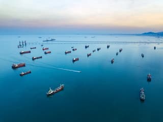 An oil tanker navigating a narrow strait with a container ship visible in the distance
