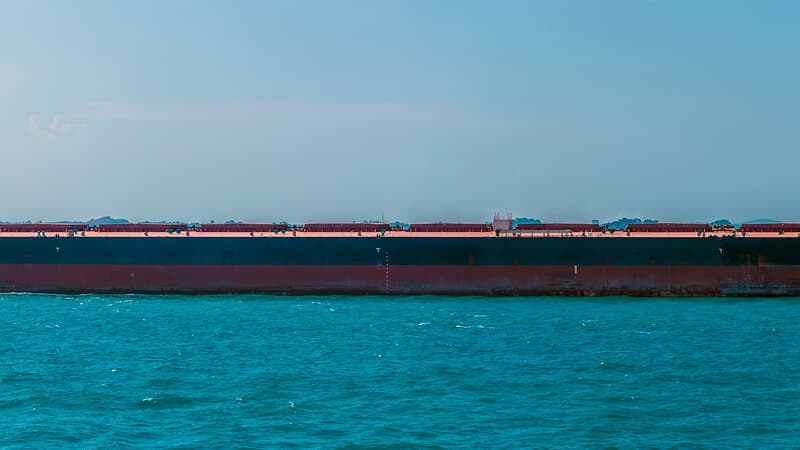 Aerial view of cargo ships and tankers moving through a narrow strait shipping lane